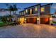 Beautiful two-story home at twilight featuring a brick-paved driveway, a three-car garage, and manicured landscaping at 4419 Ortona Ln, Wesley Chapel, FL 33543