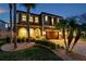 Elegant two-story home featuring a meticulously landscaped front yard, warm lighting, and a welcoming entryway at 4419 Ortona Ln, Wesley Chapel, FL 33543