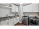 Bright laundry room with white cabinetry, granite countertops, stainless steel washer and dryer units at 4419 Ortona Ln, Wesley Chapel, FL 33543