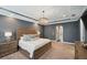 Main bedroom featuring a tray ceiling, chandelier, and ensuite bathroom access and neutral carpet at 4419 Ortona Ln, Wesley Chapel, FL 33543