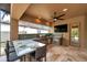 Screened outdoor kitchen with stone bar seating, a stainless steel grill, and convenient sink area at 4419 Ortona Ln, Wesley Chapel, FL 33543