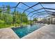 Sparkling pool enclosed within a screened lanai, providing a private outdoor oasis for relaxation and enjoyment at 4419 Ortona Ln, Wesley Chapel, FL 33543