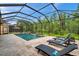 Beautiful screened-in pool with stone pavers and lounge chairs, surrounded by lush greenery at 4419 Ortona Ln, Wesley Chapel, FL 33543