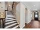 Elegant staircase with dark wood treads and white risers leading to a hallway with an arched doorway at 4419 Ortona Ln, Wesley Chapel, FL 33543