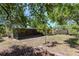Backyard view with screened in lanai, partial shade, storage shed, and tree line at 4425 W Bay Villa Ave, Tampa, FL 33611