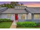 Charming single-story home featuring a red door with wreath and a well-maintained front lawn at 50 Balsam Dr, Oldsmar, FL 34677