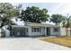 Charming single-story home with gray siding, gray shutters, covered parking, and a newly paved driveway at 551 84Th N Ave, St Petersburg, FL 33702