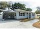 Beautifully landscaped single-story home featuring covered parking, gray siding, a modern roof, and a driveway at 551 84Th N Ave, St Petersburg, FL 33702