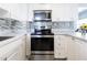 Updated kitchen with stainless steel appliances, white cabinets and drawers, stone backsplash, and tiled countertops at 551 84Th N Ave, St Petersburg, FL 33702