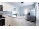 Bright kitchen with stainless steel refrigerator, modern backsplash, and white cabinetry at 551 84Th N Ave, St Petersburg, FL 33702
