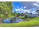 Peaceful pond surrounded by trees and lush green grass with a glimpse of nearby building structures at 10928 Brickside Ct, Riverview, FL 33579