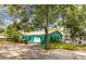 Unique teal home exterior featuring an arched porch, mature trees, and a spacious driveway with ample parking at 1108 W Virginia Ave, Tampa, FL 33603
