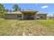 Backyard view of the home featuring a covered patio and spacious lawn at 11165 Little Gull Rd, Weeki Wachee, FL 34614