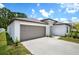A modern home with a two-car garage and a well-kept lawn under a bright, cloudy sky at 13419 Willow Bluestar Loop, Riverview, FL 33579
