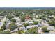 An aerial view captures a cozy single-story home nestled in a tree-filled neighborhood under a sky with a water tower in the distance at 1416 Murray Ave, Clearwater, FL 33755