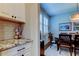 Kitchen featuring granite counters, subway tile, and white cabinets that leads to a dining area with plantation shutters at 14975 Renaissance Ave, Odessa, FL 33556
