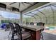 Outdoor bar area with seating overlooks the pool and lush landscaping in the screened enclosure at 14975 Renaissance Ave, Odessa, FL 33556