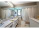 Bright bathroom with a double sink vanity, a large mirror, and a shower and bathtub at 1551 Mcauliffe Ln, Palm Harbor, FL 34683