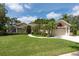 Charming single-story home featuring a well-manicured lawn and mature palm trees lining the walkway at 1551 Mcauliffe Ln, Palm Harbor, FL 34683