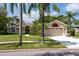 Lovely single-story home with lush landscaping, a circular driveway and an attached garage at 1551 Mcauliffe Ln, Palm Harbor, FL 34683