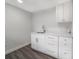 A modern kitchenette with bright white cabinets, gray floors, and a stainless steel sink at 1625 Fulton Ave, Clearwater, FL 33755