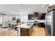 Bright kitchen with an island, wood-look floors, stainless appliances, and dark cabinets, open to the living area at 17529 Buckingham Garden Dr, Lithia, FL 33547