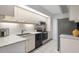 Bright galley kitchen with white cabinetry, granite countertops, stainless steel appliances, and tile flooring at 1935 Gulf Of Mexico Dr # G7-304, Longboat Key, FL 34228