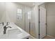 Bathroom featuring dual sink vanity, glass-enclosed shower, and white tiled walls at 2477 Water Willow Dr, Lutz, FL 33558