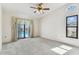 Bright bedroom featuring a ceiling fan, neutral carpet, and glass doors leading to the pool area at 254 Timberview Dr, Safety Harbor, FL 34695