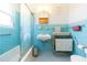 Bright bathroom with blue tiles, sink, and bathtub with glass enclosure at 34211 Blanton Rd, Dade City, FL 33523