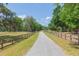 Long driveway leading to the property, framed by green trees and a wooden fence at 34211 Blanton Rd, Dade City, FL 33523