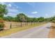 Scenic shot of the long, paved driveway that leads to the property framed by an old wooden fence at 34211 Blanton Rd, Dade City, FL 33523