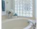 Close up of a soaking tub with chrome fixtures and a glass block window providing natural light and privacy at 3964 Silk Oak Ln, Palm Harbor, FL 34685