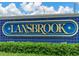Entrance sign for Lansbrook with blue and gold lettering surrounded by green shrubbery and a partially cloudy sky at 3964 Silk Oak Ln, Palm Harbor, FL 34685