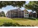 Rear exterior view of home with screened-in porch, large windows, and a lush green lawn at 3964 Silk Oak Ln, Palm Harbor, FL 34685