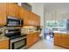 Kitchen with stainless steel appliances, granite countertops, and wood cabinets overlooking the dining area at 3964 Silk Oak Ln, Palm Harbor, FL 34685