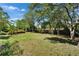 Large, well-maintained backyard with mature trees, lush lawn and a wooden fence at 402 Merlin Ct, Brandon, FL 33510