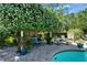 Charming backyard patio area with a beautiful flowering tree, comfortable seating, and views of the inviting pool at 402 Merlin Ct, Brandon, FL 33510
