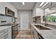 Modern kitchen features white and grey cabinets, stainless steel appliances, and granite countertops at 402 Merlin Ct, Brandon, FL 33510