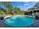 A large swimming pool is surrounded by lush landscaping, brick pavers, and a screened-in lanai in the backyard at 402 Merlin Ct, Brandon, FL 33510