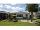 Well-maintained backyard featuring a screened-in patio, mature palm trees, and manicured landscaping at 443 Noble Faire Dr, Sun City Center, FL 33573