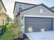 Exterior view of a home featuring a two-car garage, green grass and landscaping at 4456 Globe Thistle Dr, Tampa, FL 33619