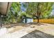 Spacious backyard featuring a storage shed, mature trees, and a wooden fence at 5628 Mccoy Ct, Zephyrhills, FL 33542