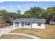 Inviting single-story home featuring a grey roof, attached garage, and landscaped yard at 5628 Mccoy Ct, Zephyrhills, FL 33542