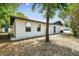 An exterior view of the home showcasing a large backyard, mature trees, and an exterior door at 5628 Mccoy Ct, Zephyrhills, FL 33542