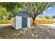 Backyard shed with painted walls, dark trim, and a brick paver entry, sitting inside of a wood fence at 5628 Mccoy Ct, Zephyrhills, FL 33542