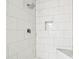 This renovated shower features white subway tile, a shower niche, and mosaic tile flooring at 5628 Mccoy Ct, Zephyrhills, FL 33542