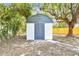 Close up of shed with a grey roof and double doors in a fenced backyard at 5628 Mccoy Ct, Zephyrhills, FL 33542