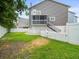 Backyard with well-kept lawn, white picket fence, and house with a second-floor deck and stairs at 619 2Nd St # 3, Indian Rocks Beach, FL 33785