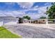 Wide exterior view of the property showcasing detached garage, carports, covered patio, and driveway at 6612 N Orleans Ave, Tampa, FL 33604